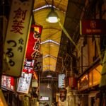 a narrow alley with signs hanging from the ceiling